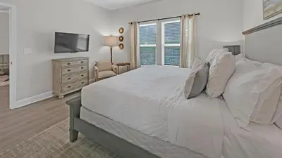 a white bedroom with a bed and a television at Once Upon a Tide - Close to Seaside on 30A and 3 blocks to beach in Santa Rosa Beach