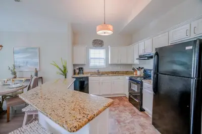 a kitchen with white cabinets and a black refrigerator at Ocean Antics - Close to the Beach and minutes to Seaside along 30A in Santa Rosa Beach