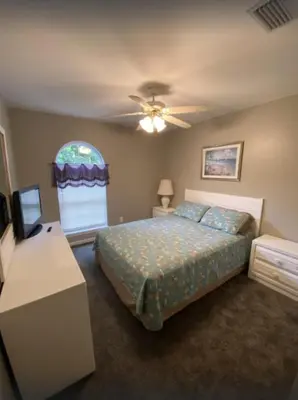 a bedroom with a bed and a table and a window at Dolphin house with Private Pool and Near Beach in Panama City Beach