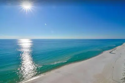 an aerial view of a beach with the sun in the sky at Dolphin house with Private Pool and Near Beach in Panama City Beach