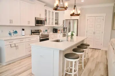 a kitchen with white cabinets and a kitchen island with stools at Peaceful Shores Retreat in Panama City Beach