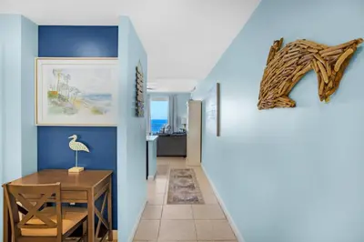 a hallway with blue walls and a table and a chair at Sterling Reef 603 in Panama City Beach