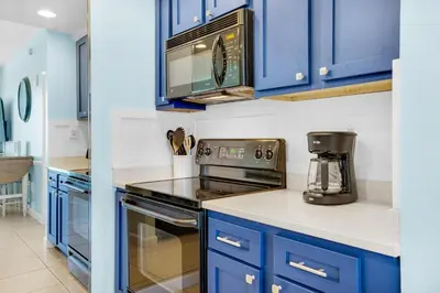 a kitchen with blue cabinets and a microwave at Sterling Reef 603 in Panama City Beach