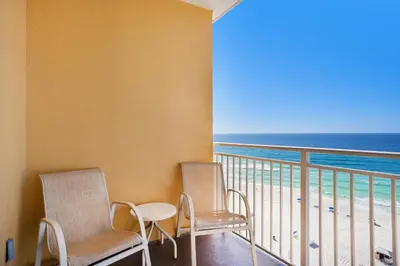 two chairs and a table on a balcony with the ocean at Sterling Reef 603 in Panama City Beach