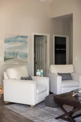 a living room with two white couches and a table at Sunset Shenanigans - Easy walk to the beach easy bike ride to Seaside in Santa Rosa Beach