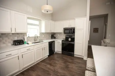 a kitchen with white cabinets and black appliances at Sunset Shenanigans - Easy walk to the beach easy bike ride to Seaside in Santa Rosa Beach