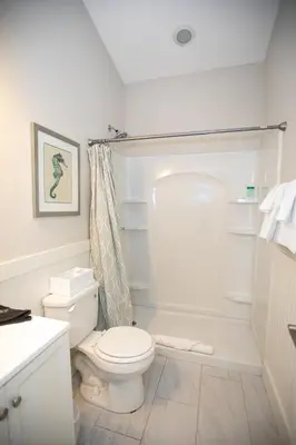 a white bathroom with a toilet and a shower at Sunset Shenanigans - Easy walk to the beach easy bike ride to Seaside in Santa Rosa Beach