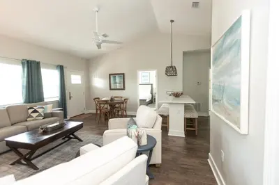 a living room with a couch and a table at Sunset Shenanigans - Easy walk to the beach easy bike ride to Seaside in Santa Rosa Beach