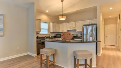 a kitchen with white cabinets and a kitchen island with stools at After Dune Delight - 3 blocks to the beach less than a mile to Seaside! in Santa Rosa Beach