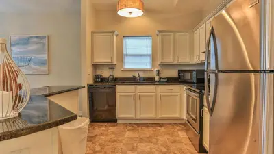 a kitchen with white cabinets and a stainless steel refrigerator at After Dune Delight - 3 blocks to the beach less than a mile to Seaside! in Santa Rosa Beach