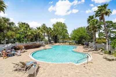 a swimming pool with chairs and palm trees at 30A Pet Friendly Beach House - Pelican's Rest by Panhandle Getaways in Rosemary Beach