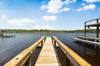 a dock on a body of water with trees in the background at 30A Pet Friendly Beach House - Pelican's Rest by Panhandle Getaways in Rosemary Beach