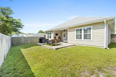 a white house with a fence and a yard at Pet Friendly Beach House - The Beach Getaway by Panhandle Getaways in Panama City Beach
