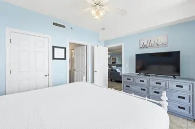 a bedroom with a white bed and a flat screen tv at Twin Palms Beach Resort by Panhandle Getaways in Panama City Beach