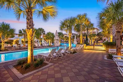 a resort pool with chairs and palm trees at 30A Beach House - Beach Bikin by Panhandle Getaways in Panama City Beach