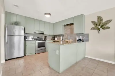 a kitchen with green cabinets and a stainless steel refrigerator at Two Spaces in One Main House and Guest House 25 Min to PCB in Panama City