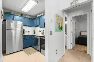a kitchen with blue cabinets and a white refrigerator at Horizon South 23A by InJoy Vacations in Panama City Beach