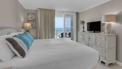 a bedroom with a bed and a television and a balcony at BeachCrest 501 in Santa Rosa Beach