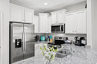 a kitchen with white cabinets and a stainless steel refrigerator at NEW ⁂Serenity Beach⁂ Lakefront 3BRs Close to Beach in Panama City Beach