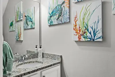 a bathroom with a sink and paintings on the wall at NEW ⁂Serenity Beach⁂ Lakefront 3BRs Close to Beach in Panama City Beach