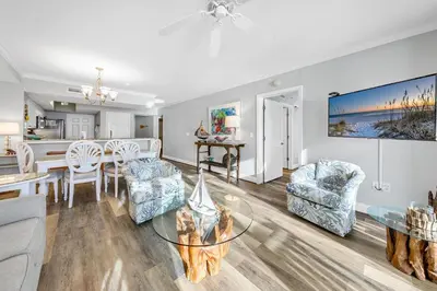a living room and dining room with a table and chairs at Emerald Beach 431 in Panama City Beach