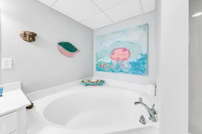 a bathroom with a white tub and a painting on the wall at Emerald Beach 431 in Panama City Beach