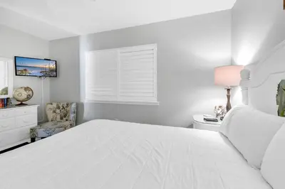 a white bedroom with a white bed and a chair at Emerald Beach 431 in Panama City Beach