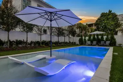 a pool with two chairs and an umbrella at Verisun - 40 Elysee Court home in Inlet Beach