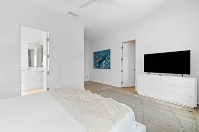 a white bedroom with a bed and a flat screen tv at Verisun - 40 Elysee Court home in Inlet Beach
