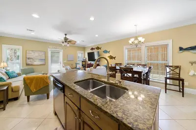a kitchen with a sink and a living room at Summer Special, Lux 4BR House Sleeps 12, Pool, Elevator, King bed in Panama City Beach