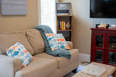 a living room with a brown couch with two pillows at Summer Special, Lux 4BR House Sleeps 12, Pool, Elevator, King bed in Panama City Beach