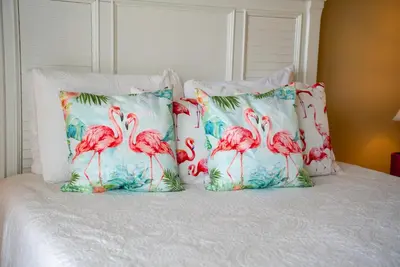 a bed with four pillows with flamingos on it at Summer Special, Lux 4BR House Sleeps 12, Pool, Elevator, King bed in Panama City Beach
