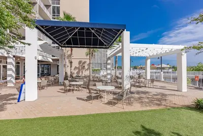 a patio with tables and chairs in a building at Remodeled Resort Condo! Ocean & Beach Views by Dolce Vita Getaways PCB in Panama City Beach