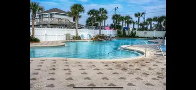 a large swimming pool in a yard with a house at Stunning Ocean & Sunset Views, Direct Beach Access with 2 King Bedrooms at Panama City Beach, Fl in Panama City Beach
