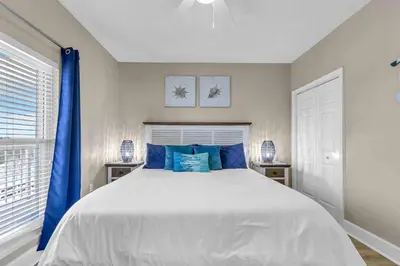 a bedroom with a large white bed with blue pillows at Stunning Ocean & Sunset Views, Direct Beach Access with 2 King Bedrooms at Panama City Beach, Fl in Panama City Beach