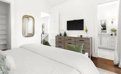 a white bedroom with a bed and a tv at Found My Zen in Rosemary Beach