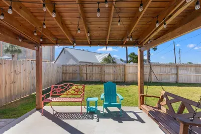 a wooden pergola with chairs and a table at Coral Cabana - 3BD 2BA Home Close to Beach w/ optional Golf Cart! in Panama City Beach