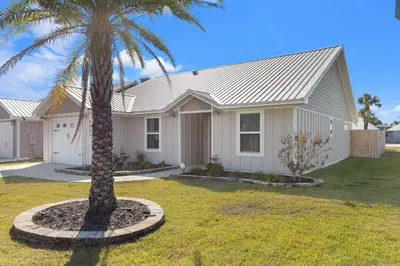 a house with a palm tree in the front yard at Coral Cabana - 3BD 2BA Home Close to Beach w/ optional Golf Cart! in Panama City Beach
