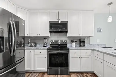 a kitchen with white cabinets and a stove top oven at Coral Cabana - 3BD 2BA Home Close to Beach w/ optional Golf Cart! in Panama City Beach