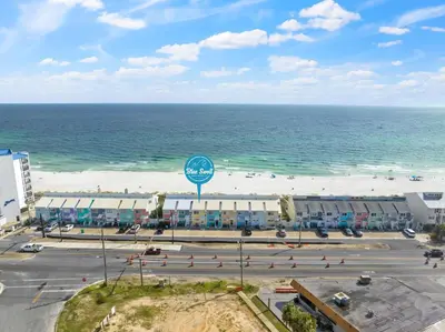 an aerial view of a beach with a sign and the ocean at 2BD/25BA Gulf Front Townhome near Pier Park! Gulf Views! Beach Access! in Panama City Beach