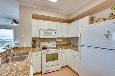 a kitchen with white cabinets and a white refrigerator at Panama City Beach Condo Balcony with Ocean Views! in Panama City Beach