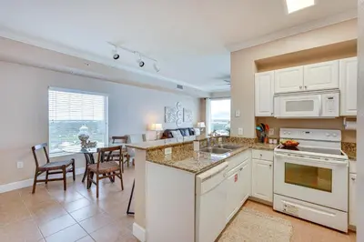 a kitchen with white cabinets and a dining room at Panama City Beach Condo Balcony with Ocean Views! in Panama City Beach