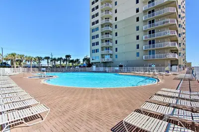 a swimming pool with lounge chairs and a building at Panama City Beach Condo Balcony with Ocean Views! in Panama City Beach