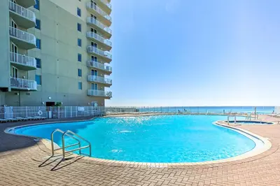 a swimming pool in front of a building and the ocean at Panama City Beach Condo Balcony with Ocean Views! in Panama City Beach