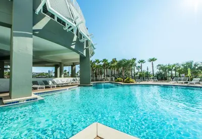 a swimming pool at a resort with chairs and palm trees at Laketown Wharf 607 in Panama City Beach
