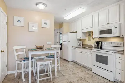 a kitchen with white cabinets and a table and chairs at Merrimac Resort #31 in Panama City Beach