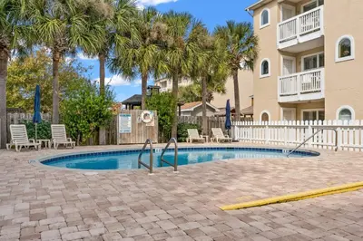 a swimming pool with chairs and palm trees at Merrimac Resort #31 in Panama City Beach