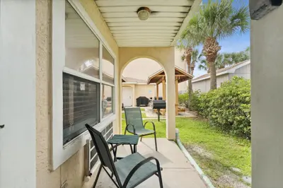 a porch with chairs and a window and palm trees at Merrimac Resort #41 in Panama City Beach