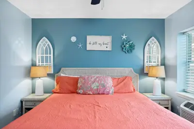 a blue bedroom with a bed with orange sheets and two lamps at Merrimac Resort #41 in Panama City Beach