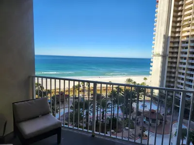 a room with a balcony with a chair and the beach at Updated Beach Condo at the Shores of Panama Condos - Unit 918 in Panama City Beach